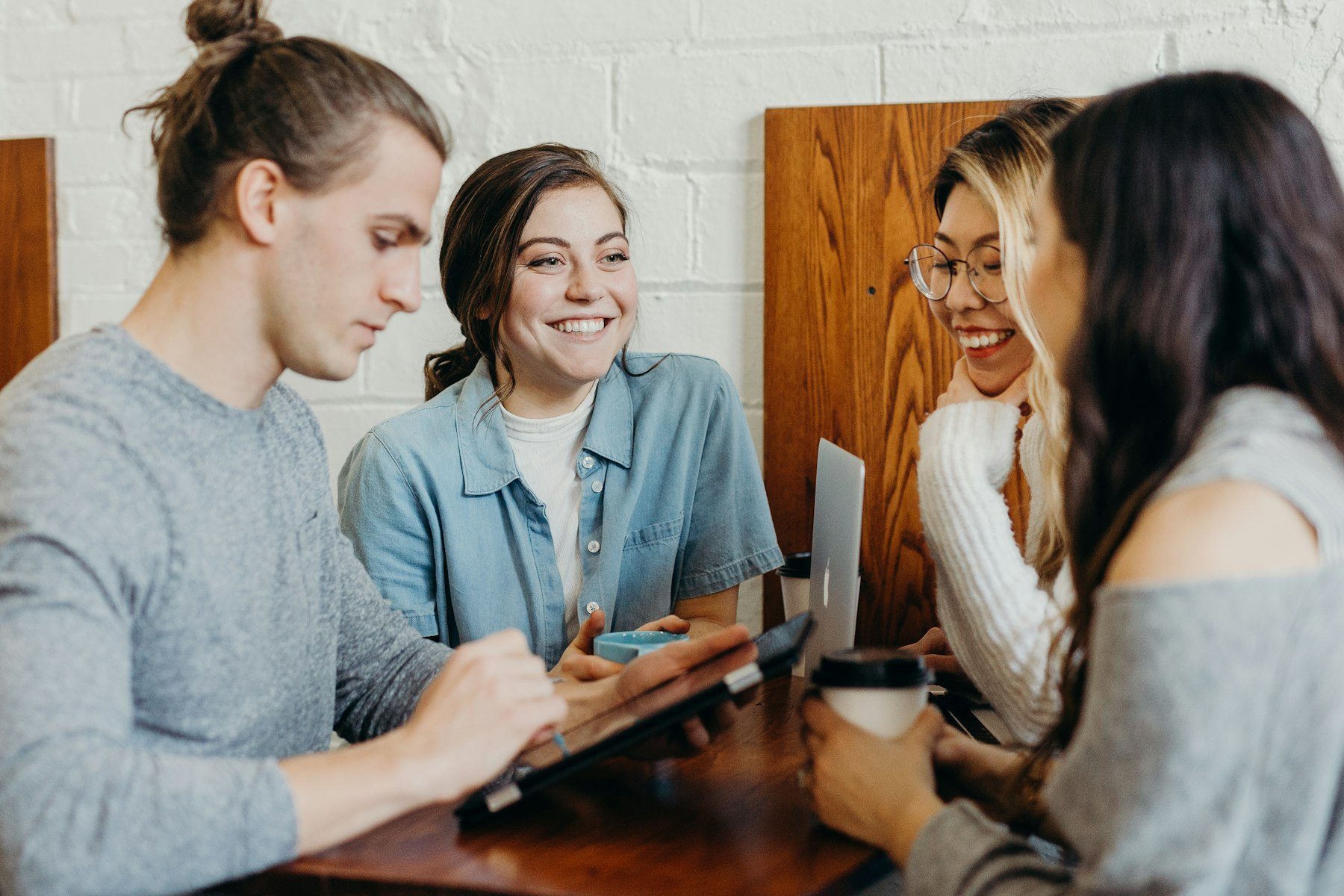 Four coworkers laughing together around a laptop